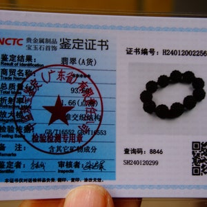 May include: A black beaded bracelet rests on a white document with Chinese text and a seal. The document also includes a QR code and the text "NCTC". The bracelet is made of round, dark beads.