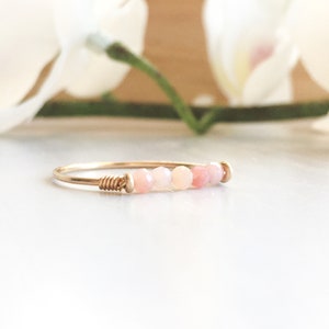 Pu&ograve; includere: Un delicato anello d'oro con una fila di perline rosa e bianche. La fascia dell'anello &egrave; sottile e avvolta con filo ad un'estremit&agrave;, con un design semplice ed elegante. Le perline presentano una sfumatura di tenui tonalit&agrave; rosa.