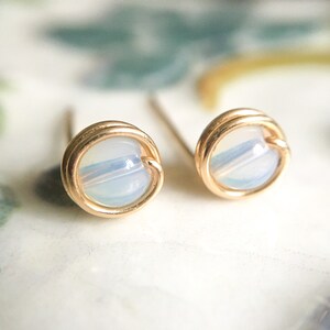 May include: A pair of gold wire wrapped earrings with iridescent white opal beads.