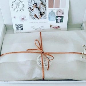 May include: A white cardboard shipping box containing a package wrapped in white tissue paper, tied with a copper-colored ribbon and a round Wild Ivy tag. A printed card with the Wild Ivy logo, a QR code, and product photos is inside the box.