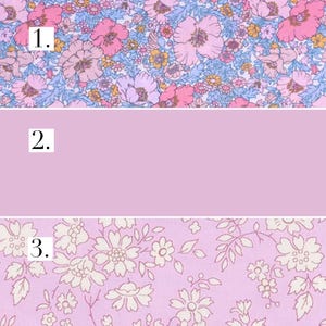 May include: Three fabric swatches with different floral patterns. The first swatch has a pink, blue and white floral pattern. The second swatch is solid pale pink. The third swatch has a white floral pattern on a pale pink background.