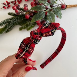 Può includere: Una fascia per capelli a quadri rossi con fiocco. La fascia presenta un classico motivo tartan in rosso, nero e giallo. Il fiocco è centrato sulla fascia, creando un accessorio festivo. Ideale per le festività natalizie.