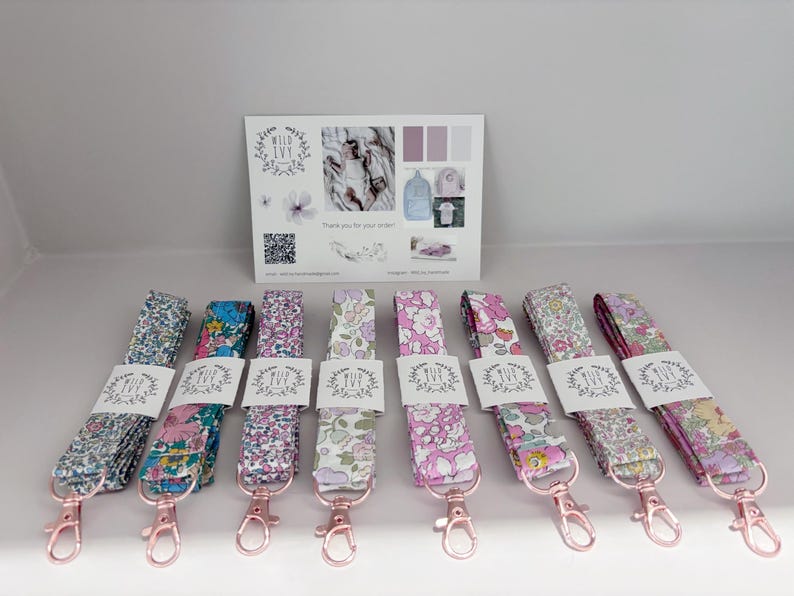 May include: A selection of floral lanyards with rose gold-coloured clasps. Each lanyard is wrapped with a white label with the text "Wild Ivy". A card with the Wild Ivy logo and other graphics is in the background.