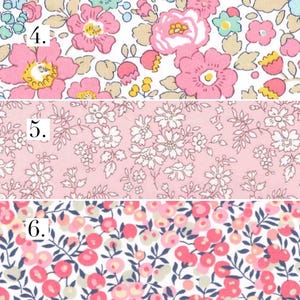May include: Three different fabric swatches with floral patterns. The first swatch has a white background with pink and yellow flowers. The second swatch has a pink background with white flowers. The third swatch has a white background with pink and red berries.
