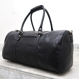 May include: Black leather duffel bag with a crocodile embossed pattern and gold hardware.