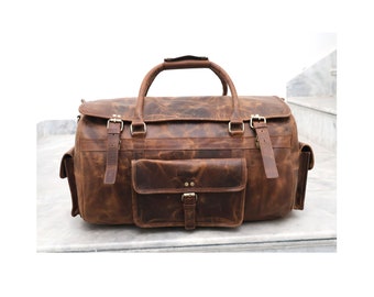 May include: A brown leather duffel bag with a large front pocket and two side pockets. The bag has a top handle and a zipper closure.