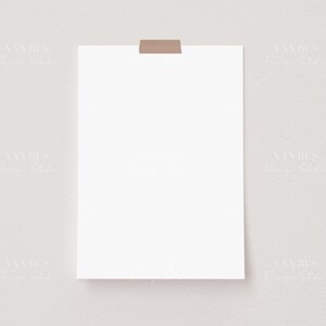 May include: A blank white sheet of paper taped to a light gray wall. The paper is square shaped and has a brown tape strip at the top.