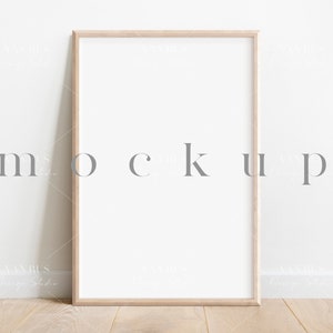 May include: A light wood frame with a white mat and a white background. The frame is sitting on a light wood floor against a white wall.