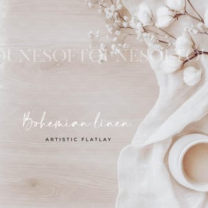 Könnte beinhalten: Ein Flatlay mit einem weißen Leinenstoff mit weißen Blumen und einer weißen Keramiktasse mit einem beigefarbenen Getränk. Der Text "Bohemian linen" und "Artistic Flatlay" ist in Weiß auf einem hellen Holzhintergrund geschrieben.