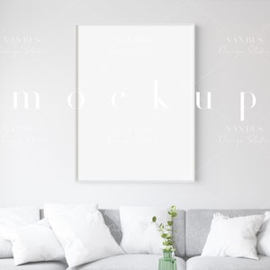 Könnte beinhalten: Ein weiß gerahmter Mockup eines vertikalen Posters an einer hellgrauen Wand. Das Wort "Mockup" ist schwach sichtbar. Darunter ist ein graues Sofa mit weißen Kissen und einer grünen Vase mit Grün geschmückt.