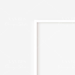 May include: A white picture frame with a white mat is hanging on a white wall.