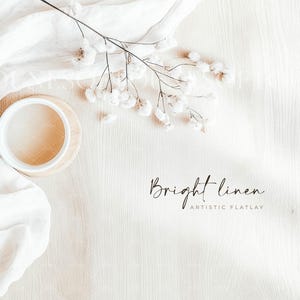 Könnte beinhalten: Eine weiße Keramiktasse mit einem Untersetzer aus Holz steht auf einer hellen Holzoberfläche. Ein weißes Leinen-Tuch hängt über die linke Seite des Bildes. Ein Zweig weißer Baby's Breath Blumen befindet sich auf der rechten Seite des Bildes. Der Text "Bright linen" und "Artistic Flatlay" ist in schwarzer Kursivschrift geschrieben.