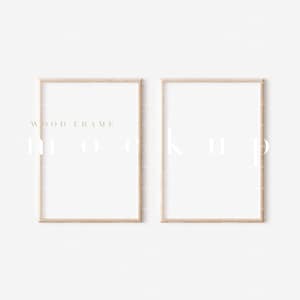 Op de afbeelding: Twee houten fotolijsten met een lichtbruine afwerking. De lijsten zijn leeg en klaar voor een foto of kunstwerk. De lijsten hangen aan een witte muur.