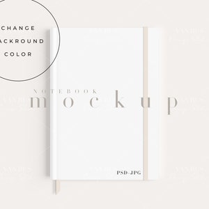 Op de afbeelding: Witte notitieboek mockup met een beige lint-bladwijzer. Het notitieboek heeft de tekst "NOTEBOOK MOCKUP" gedrukt op de voorzijde. De tekst "PSD.JPG" is gedrukt in de rechterbenedenhoek van het notitieboek.