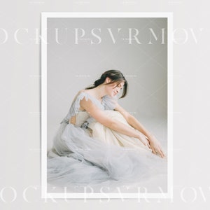 May include: A woman in a light blue tulle dress sits on a white floor with her head down. The dress has a white bodice with a ruffled neckline.