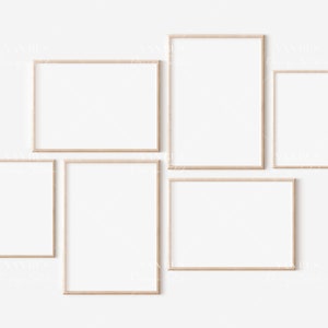 May include: Five empty picture frames of various sizes are arranged on a white wall. The frames are made of light wood and have a simple, modern design.