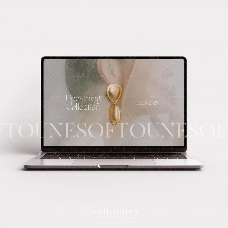 Może przedstawiać: Laptop wyświetla reklamę biżuterii. Na ekranie widnieje złoty kolczyk z g&oacute;rą w kształcie serca i dołem w kształcie łzy. Tekst na ekranie brzmi "Upcoming Collection" i "02.05.2025". Laptop jest srebrny i stoi na białej powierzchni.