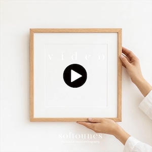 May include: A square, light-coloured wooden frame with a white mount. The frame holds a white background with the word "video" in light grey text and a black circle with a white play button. The bottom of the frame has the text "softounes".