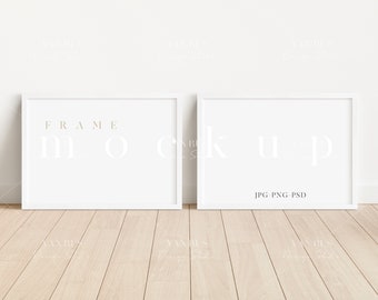May include: Two white picture frames with white mats on a light wood floor. The frames are empty and ready for your artwork. The text "FRAME MOCK UP JPG PNG PSD" is printed on the bottom of the right frame.