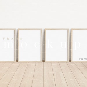 Pode incluir: Quatro molduras de madeira natural com passe-partout brancos, dispostas horizontalmente em um piso de madeira clara. As molduras estão vazias e prontas para suas fotos ou obras de arte. O texto "FRAME MOCKUP JPG PSD" é visível no canto inferior direito.