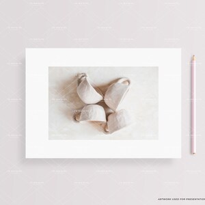 May include: Four white ceramic cups arranged in a circle on a light beige surface. The cups are slightly tilted and have a simple, minimalist design.