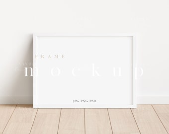 May include: White frame mockup on a light wood floor against a white wall. The frame is empty and ready for your design.