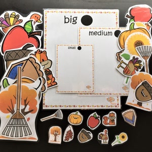 Könnte beinhalten: Ein Satz druckbarer Herbst-Lernkarten für Kinder. Die Karten zeigen Bilder von einem Kürbis, Apfel, Eichel, Truthahn, Rechen und einer Torte. Die Karten sind mit den Wörtern "groß", "mittel" und "klein" beschriftet.