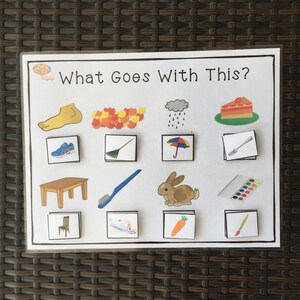 May include: A colorful educational game for kids with the text "What Goes With This?"  The game features images of a foot, leaves, rain, cake, shoes, a rake, an umbrella, a fork, a table, a toothbrush, a rabbit, paint, a chair, toothpaste, a carrot, and a paintbrush.
