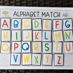 May include: A colorful alphabet matching game with the letters A through Z printed on individual squares. The letters are in different colors and are arranged in rows on a white background. The title "Alphabet Match ABC" is printed at the top of the game.
