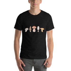 Może przedstawiać: Czarny T-shirt z nadrukiem sześciu r&oacute;żnych rodzaj&oacute;w grzyb&oacute;w na przodzie. Grzyby są w odcieniach brązu, bieli i ż&oacute;łci.