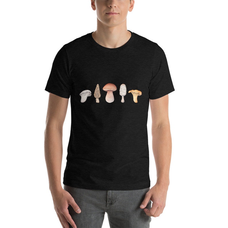 Może przedstawiać: Czarny T-shirt z nadrukiem sześciu r&oacute;żnych rodzaj&oacute;w grzyb&oacute;w na przodzie. Grzyby są w odcieniach brązu, bieli i ż&oacute;łci.