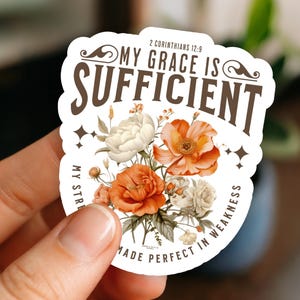 May include: A sticker with the text "MY GRACE IS SUFFICIENT" and the Bible verse 2 Corinthians 12:9. The sticker features a floral design with orange and white flowers. The words "MADE PERFECT IN WEAKNESS" are also included.