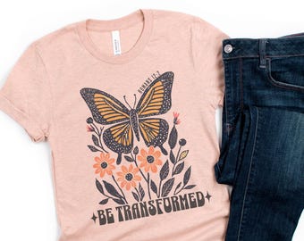 Camiseta cristiana con versículo bíblico "Sé transformado", estilo bohemio con mariposas y escrituras.