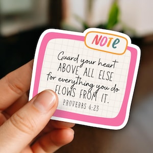 May include: A rectangular sticker with a pink border and the word "NOTE" in an orange and teal bubble. The sticker features the text "Guard your heart ABOVE ALL ELSE for everything you do FLOWS FROM IT. PROVERBS 4:23."