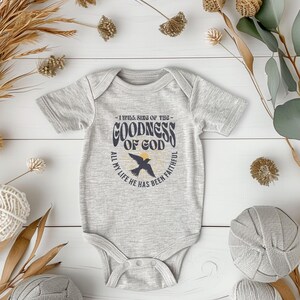 May include: A grey baby onesie with a graphic print of a bird and the text "I will sing of the goodness of God, all my life he has been faithful".