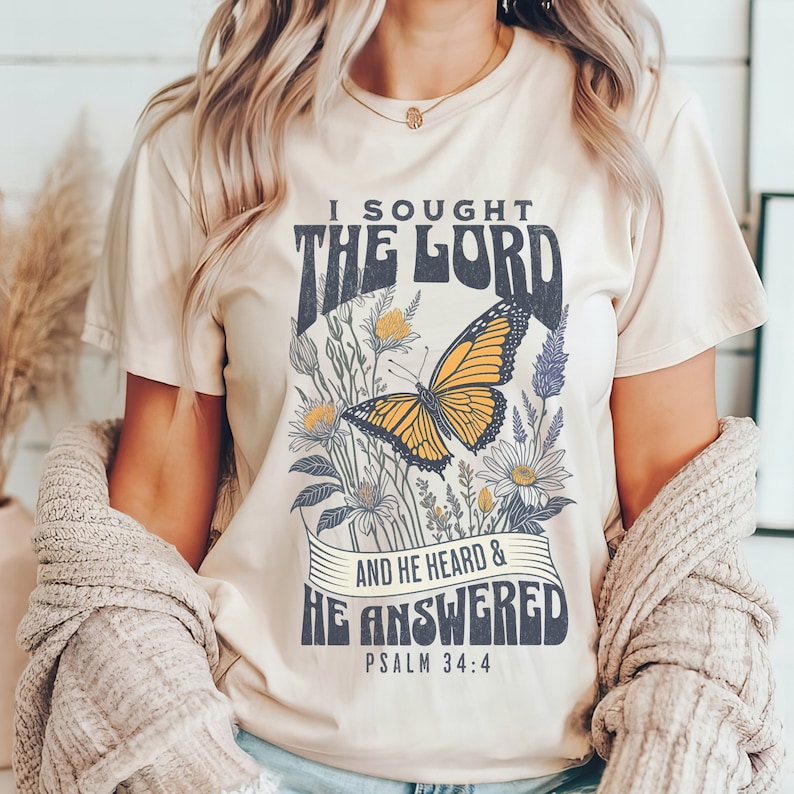May include: A beige t-shirt with a floral design and a butterfly. The text on the shirt reads "I sought the Lord and he heard & he answered Psalm 34:4".