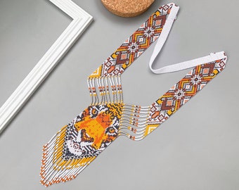 May include: A white beaded necklace with a tiger face design in orange, brown, and white. The necklace has a white cord and a fringe of beads.