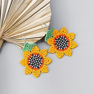 May include: A pair of beaded sunflower earrings with green leaves. The earrings are made of small, colorful beads and have a delicate, feminine look.