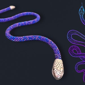 Op de afbeelding: Een kralen slangenketting met een zilveren slangenkop bedel. De slang is paars en blauw met een verloop effect. De ketting ligt op een zwarte achtergrond.