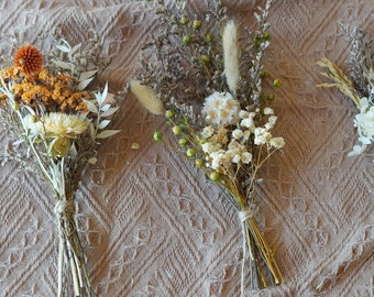 May include: Three small bouquets of dried flowers. The bouquets are tied with twine and feature a variety of dried flowers in shades of white, cream, and orange.