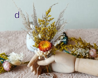 May include: A bouquet of dried flowers in shades of yellow, orange, and white. The bouquet includes dried grasses and a single orange flower.