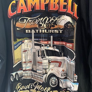 May include: Black t-shirt with a graphic of a white semi-truck with the text "D.A. Campbell Transport Bathurst Bad Moor Rising" printed on the back.