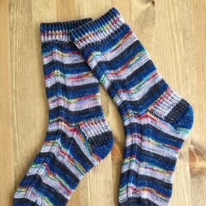 May include: A pair of striped socks in shades of blue, grey, and pink. The socks are knitted and have a textured pattern.