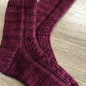 May include: A pair of burgundy knitted socks with a cable knit pattern.