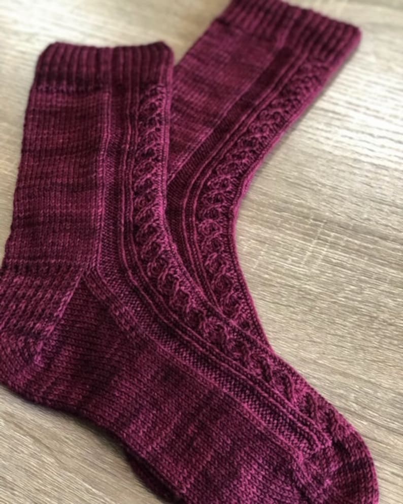 May include: A pair of burgundy knitted socks with a cable knit pattern.