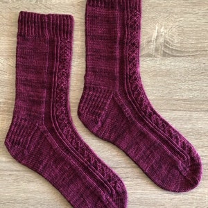 May include: A pair of hand-knitted socks in a deep burgundy colour with a cable knit pattern.