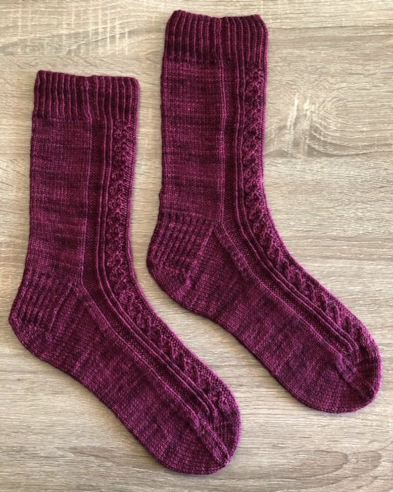May include: A pair of hand-knitted socks in a deep burgundy colour with a cable knit pattern.