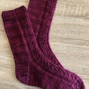 May include: A pair of knitted socks in a deep burgundy colour with a cable knit pattern.