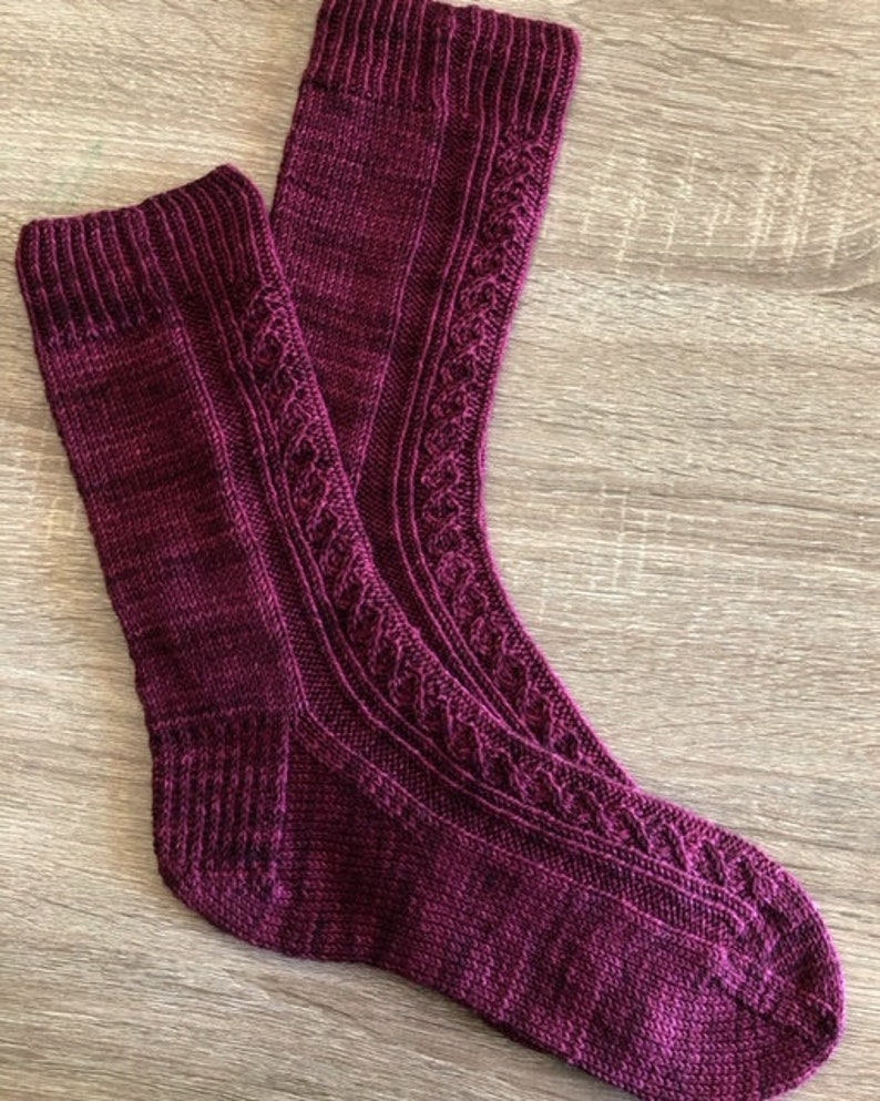 May include: A pair of knitted socks in a deep burgundy colour with a cable knit pattern.