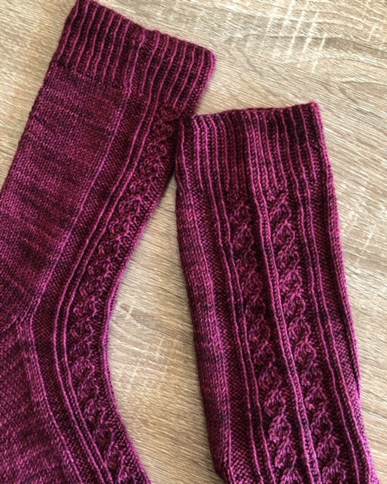 May include: A pair of burgundy knitted socks with a cable knit pattern.